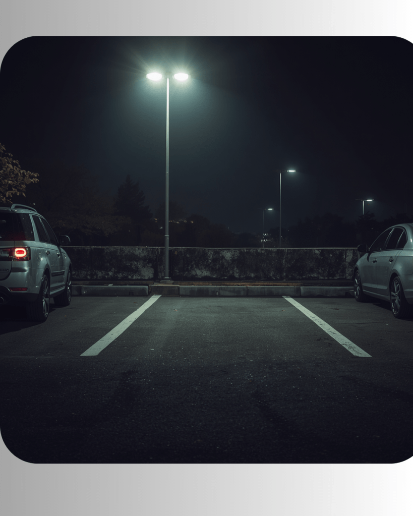 Een nachtelijke parkeerplaats met twee geparkeerde auto's en straatverlichting.