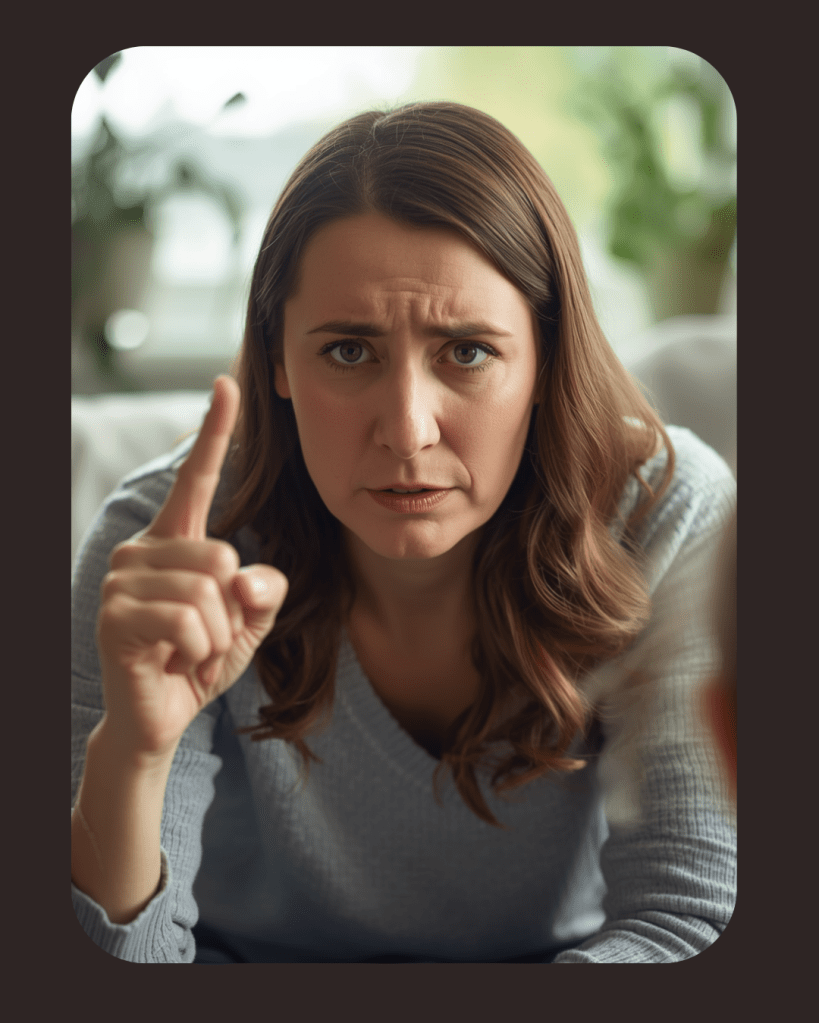 Een vrouw die ernstig kijkt en met één vinger omhoog wijst, terwijl ze spreekt. Ze heeft een lichte trui aan en een betrokken houding.